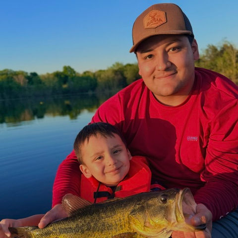 Ben holding his first fish beside his dad Angel